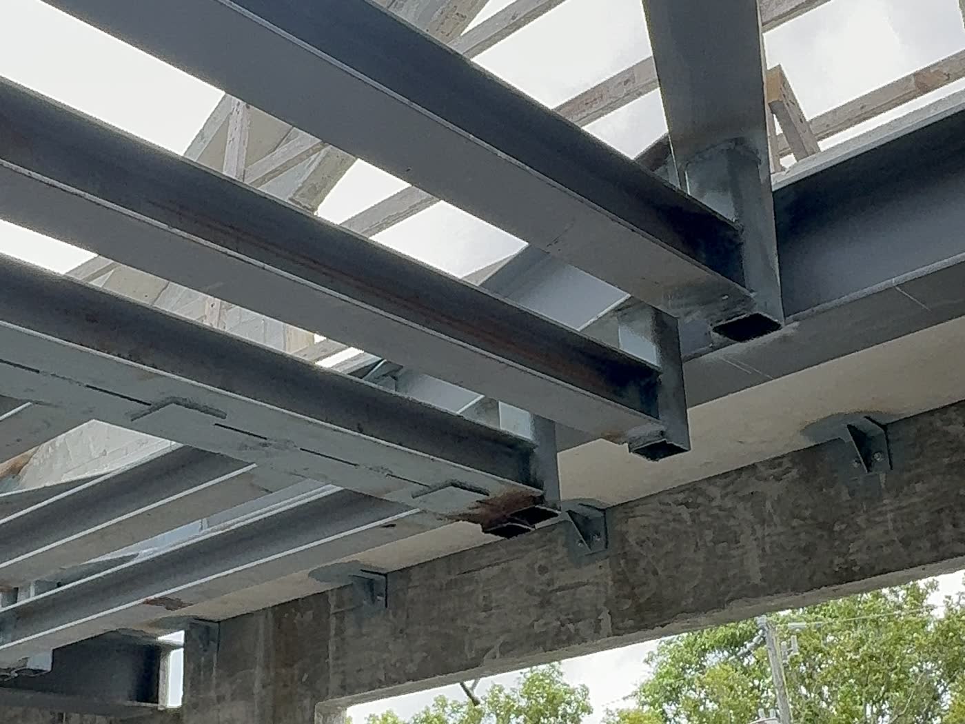 Vigas de acero estructural cubriendo una abertura, vistas desde abajo contra el cielo abierto.
