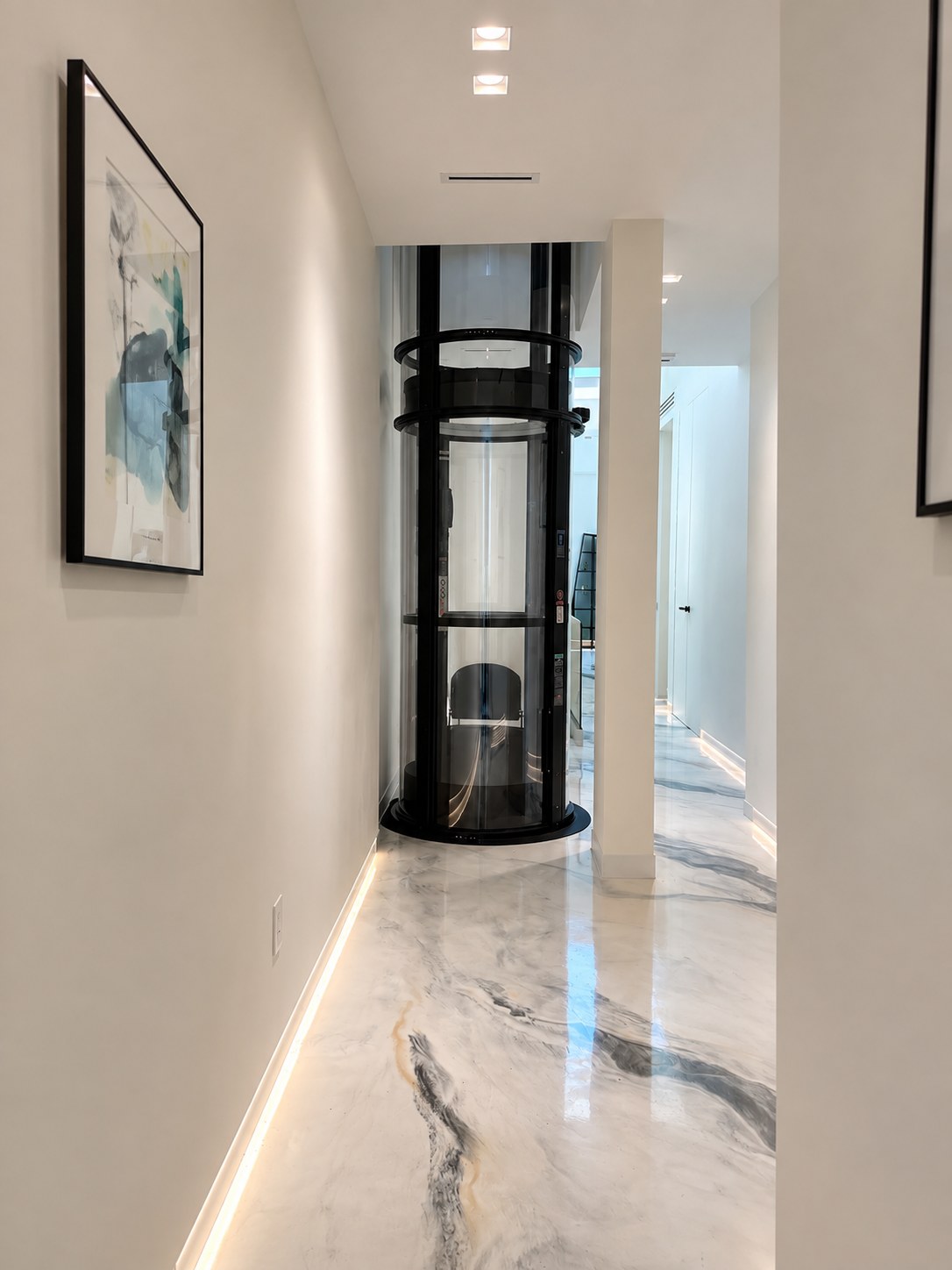 Desde el pasillo. El elevador queda al final del recorrido, con la iluminación LED de rodapié pasando por su base y el…