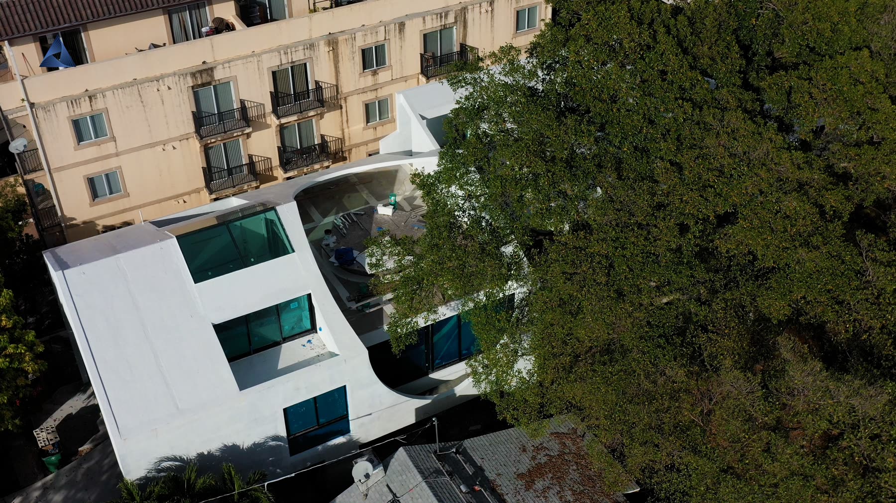 From the street. The dark glazing sits flush in the white mass so the building reads as a solid with pieces removed.