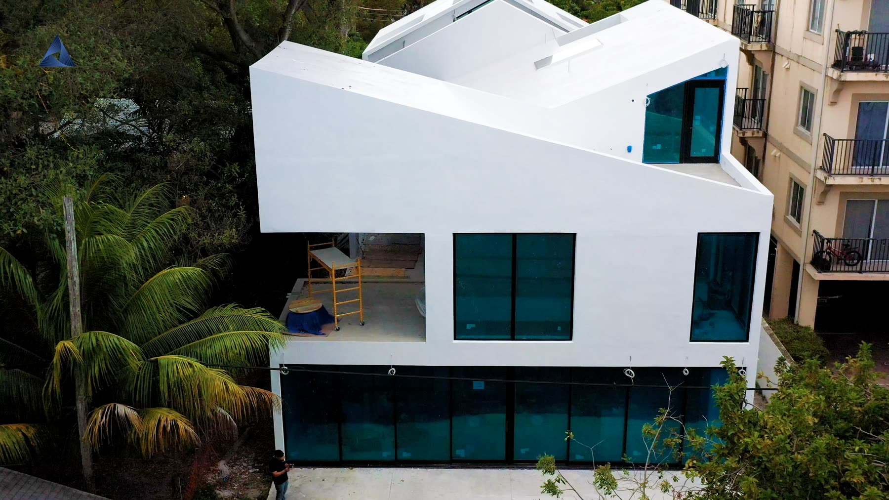 The finished white house with full-height dark glazing set into the facade.