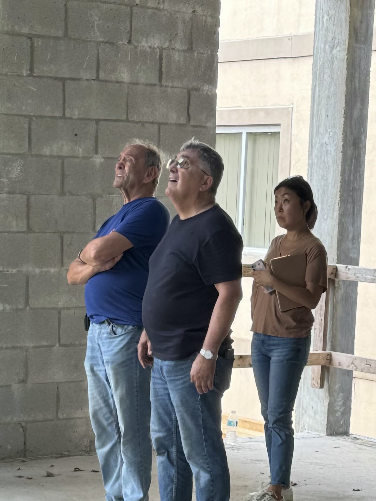 John, Leslie y la arquitecta en el piso de planta baja durante la etapa de la cáscara, los tres mirando hacia arriba la…