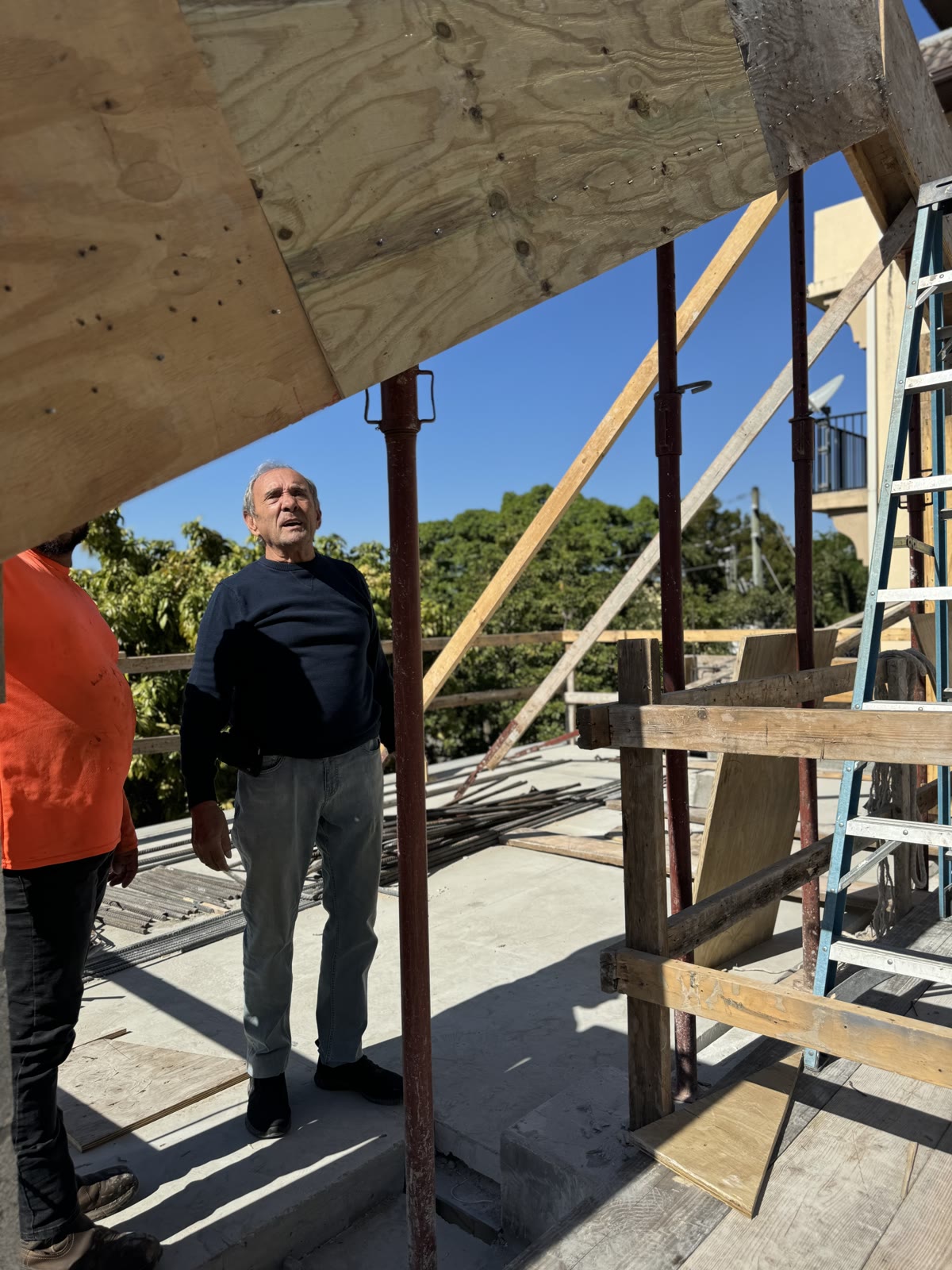 Leslie Gratz standing under the shoring on the deck, looking up at the structure going in above him.