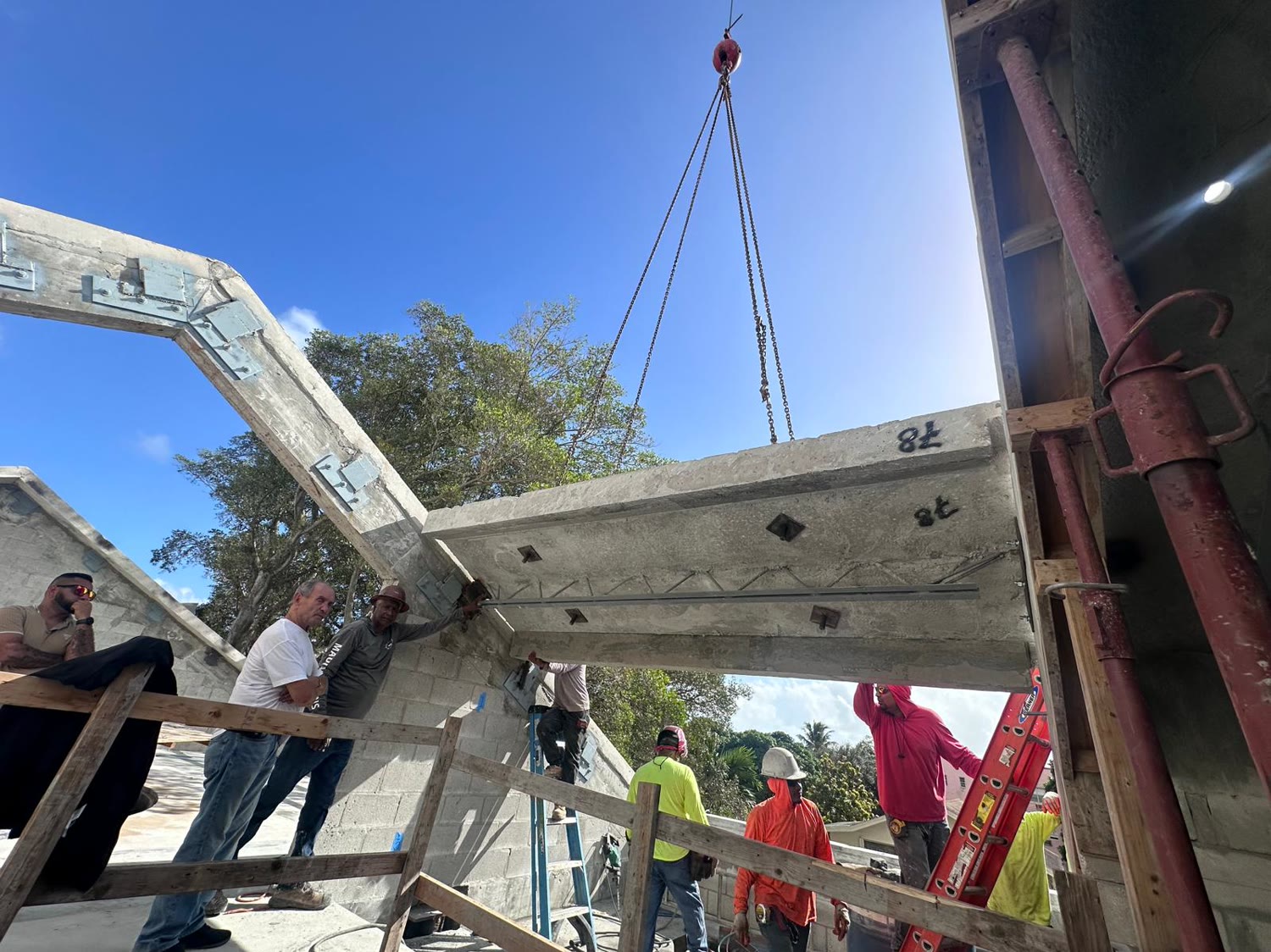 A precast beam coming down onto its bearing. Leslie watching it land — the pieces arrive finished and there is exactly…