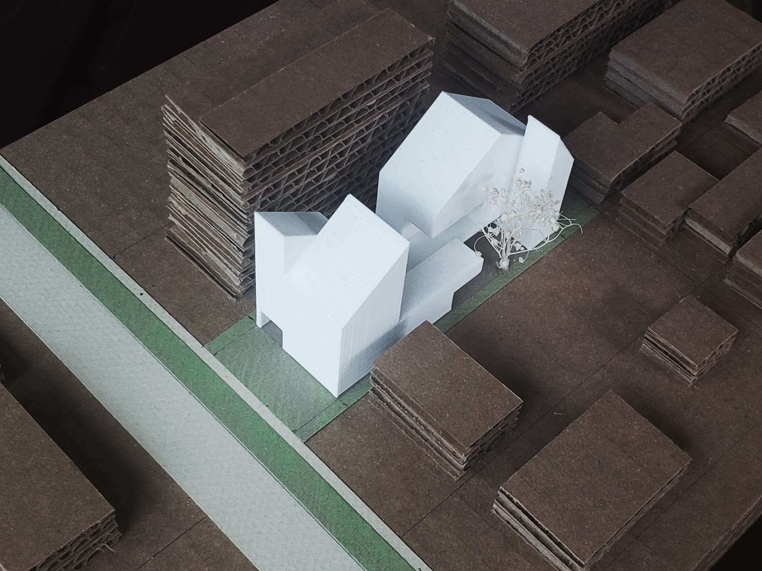 Y sostenido contra el propio terreno — la maqueta delante, la manzana real detrás, probando si pertenece a la calle…