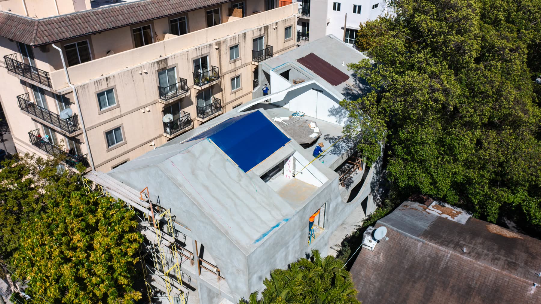 Aerial of the concrete shell at full height, the neighbouring building hard against the right side with no gap between them.