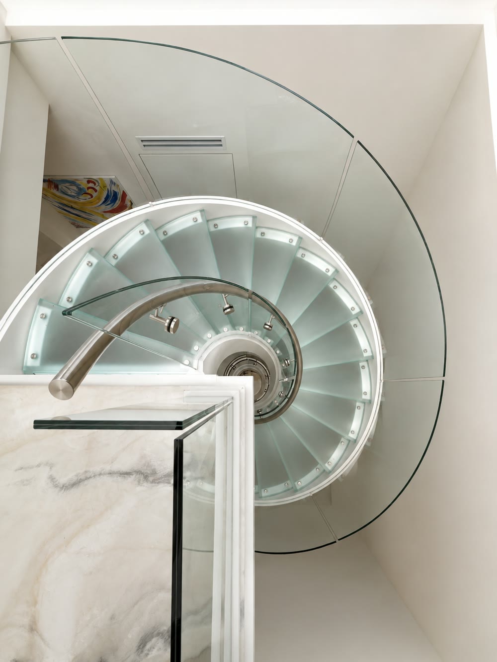 Finished, from the floor above. Twenty-odd laminated glass treads turning on the steel core, the curved glass guard…