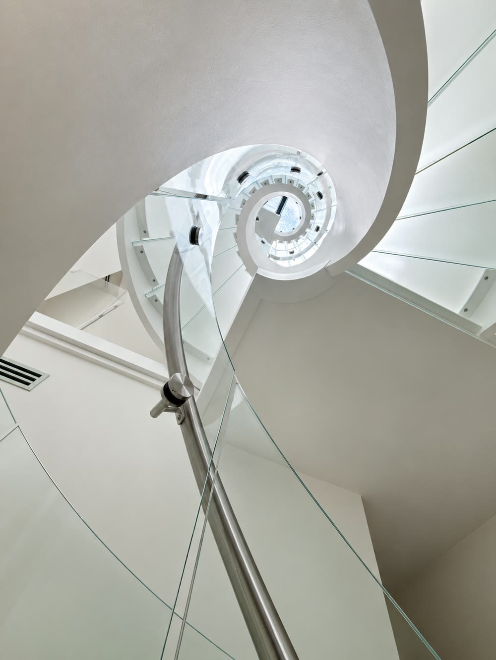 And from below, looking up. The same helix read in reverse: the treads stacked into the spiral, the curved balustrade…
