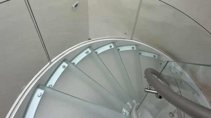 Mirando hacia abajo la espiral montada: peldaños de vidrio laminado y la baranda de acero inoxidable.